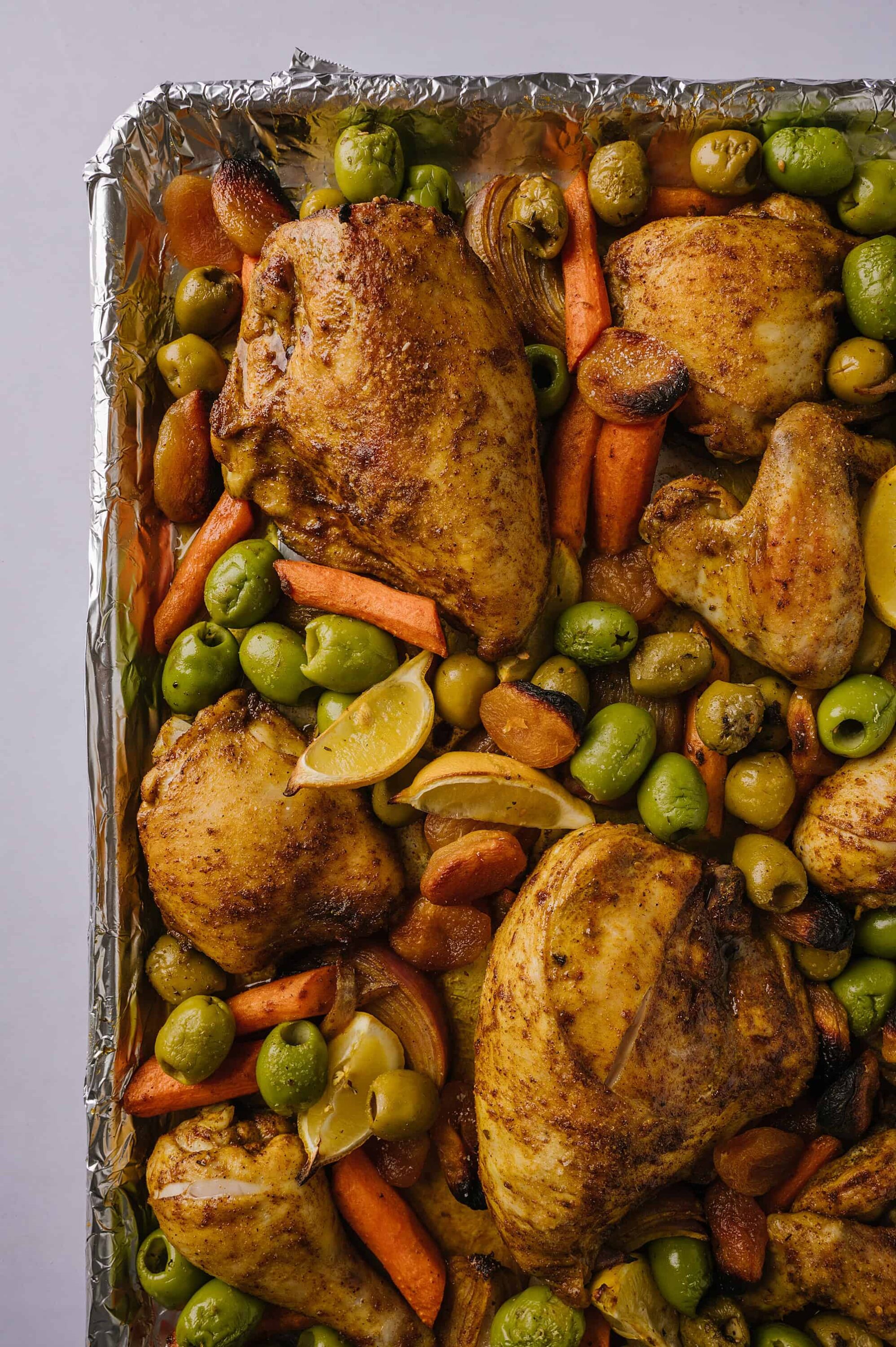Roasted chicken thighs with vegetables in baking sheet.