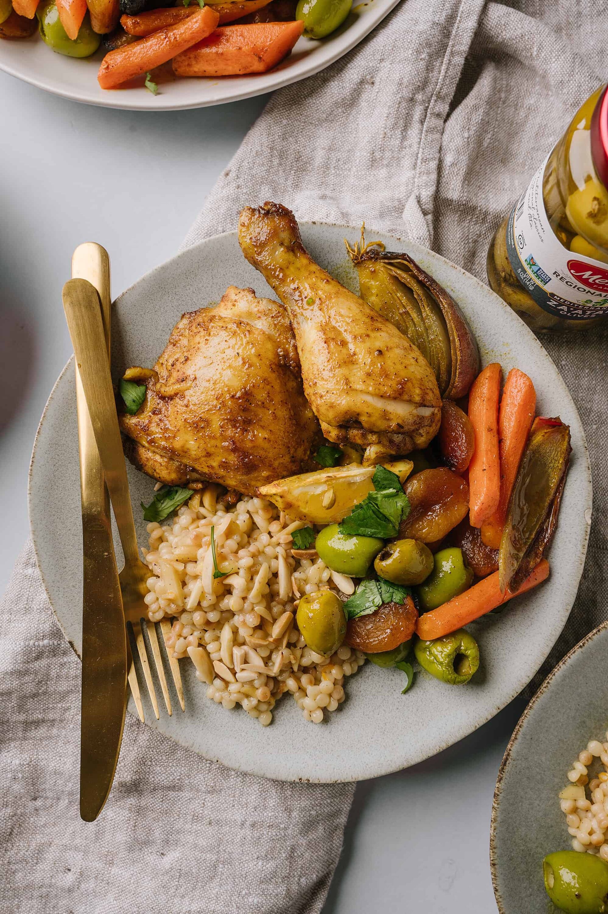 Roasted chicken with Mediterranean vegetables and orzo pasta on a ceramic plate.