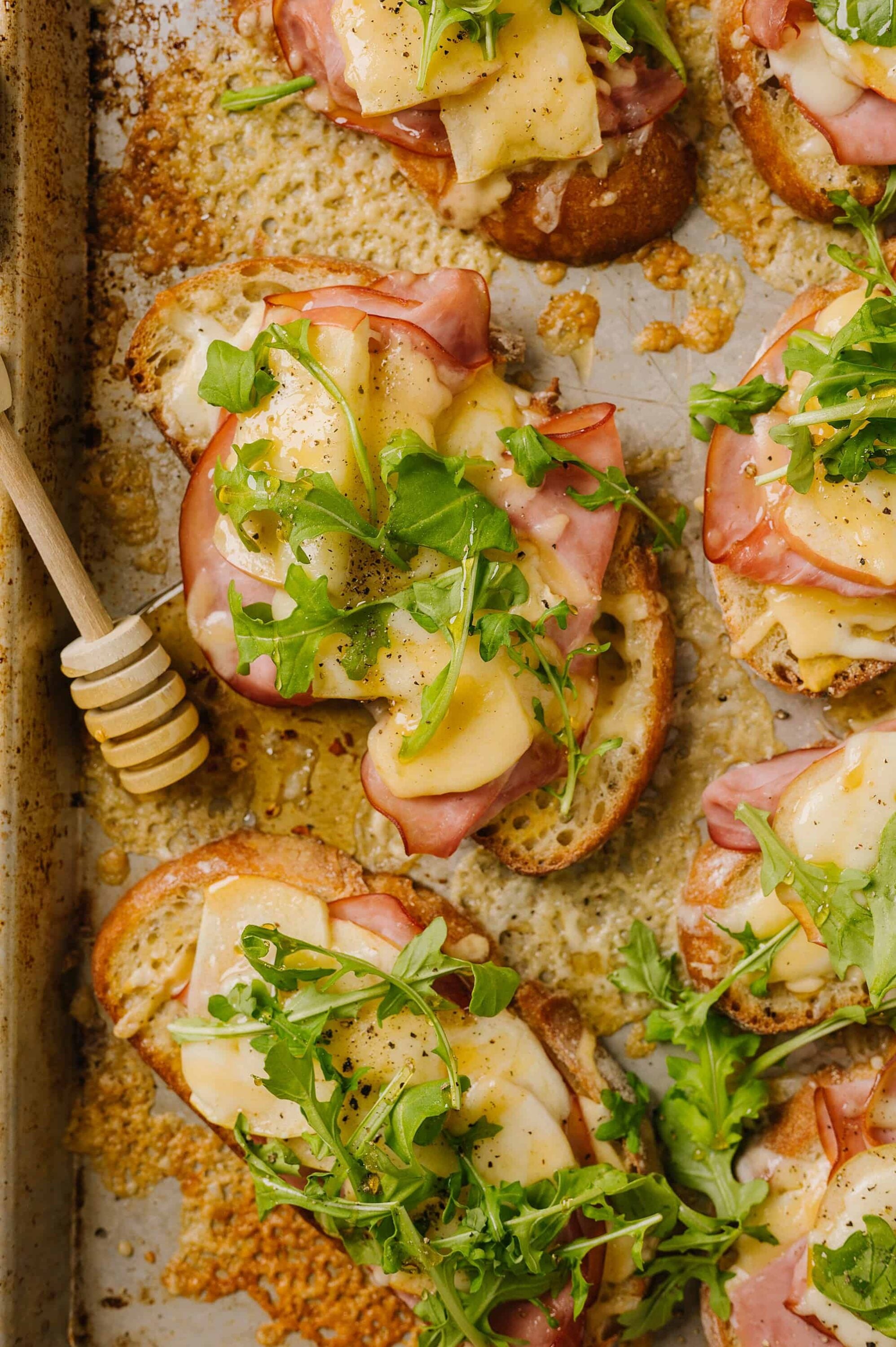 Savory open-faced sandwiches with ham, cheese, and greens on toasted bread.