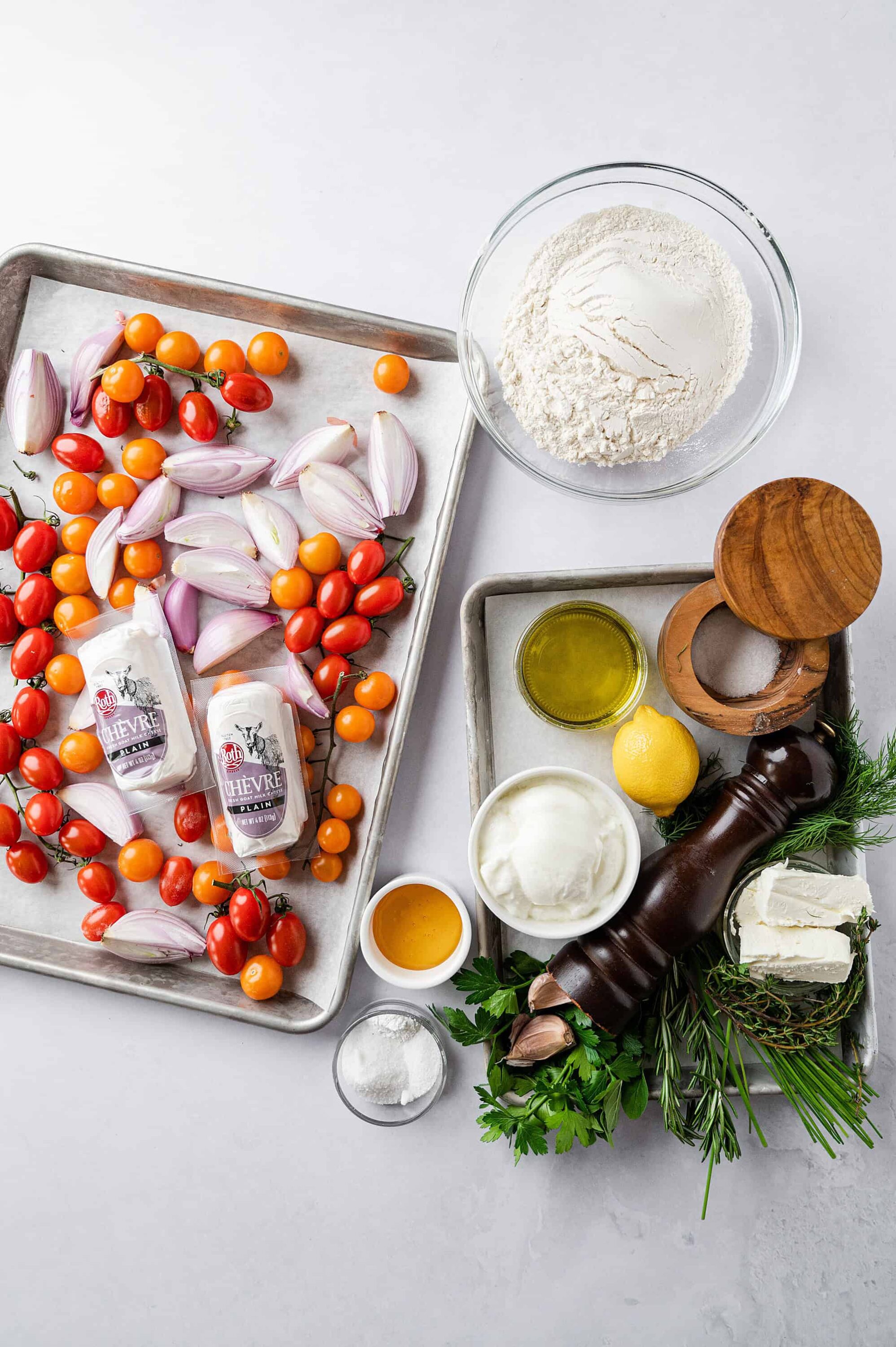 Fresh cherry tomatoes, shallots, and ingredients for cooking or baking on a white surface, prepared for a recipe.