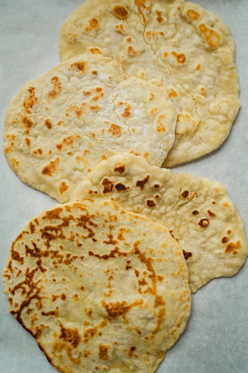Soft homemade flour tortillas on parchment paper, perfect for Mexican recipes and wraps.