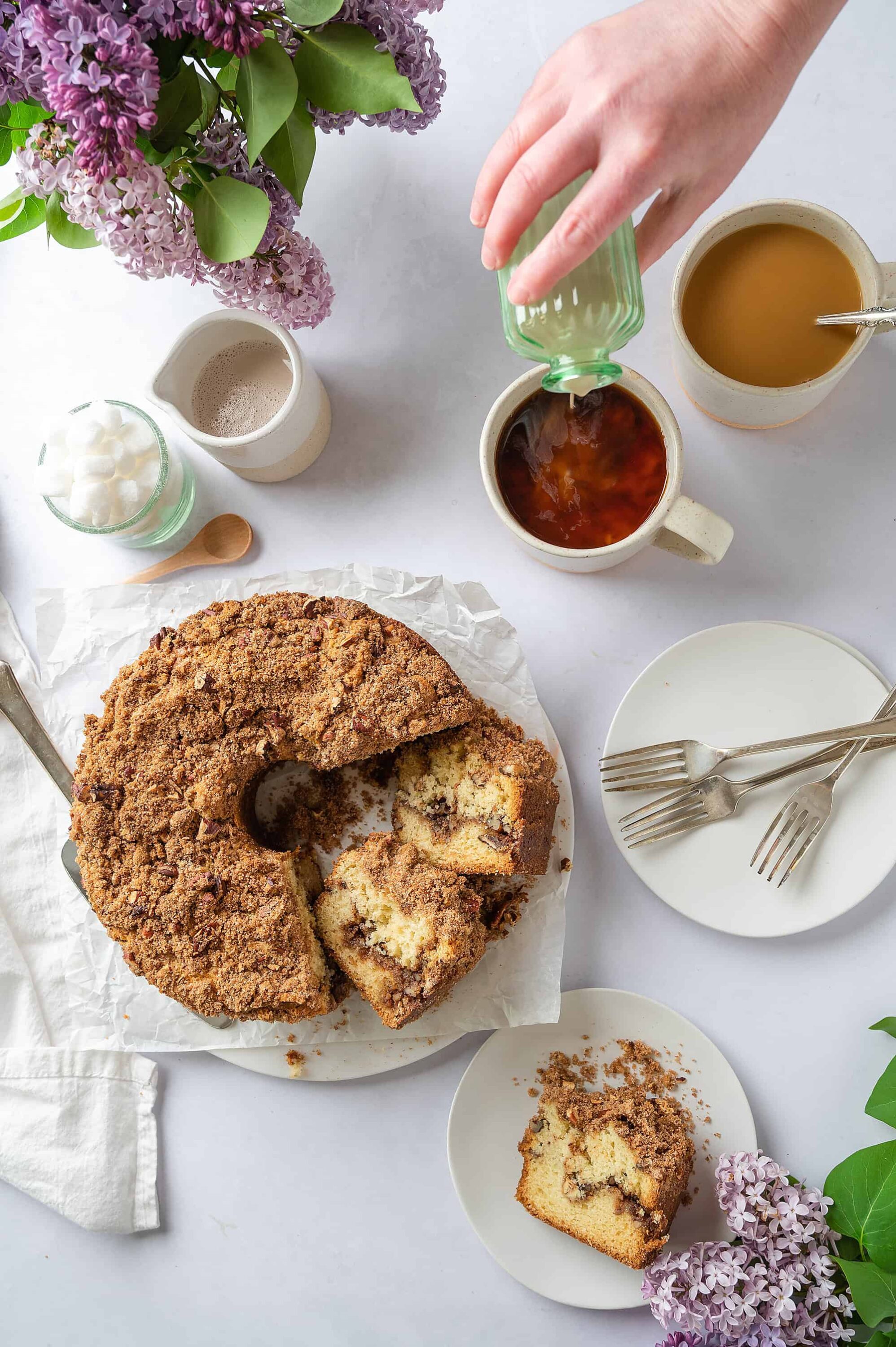 Freshly baked crumb cake with coffee and tea, topped with flower decoration for brunch or dessert.