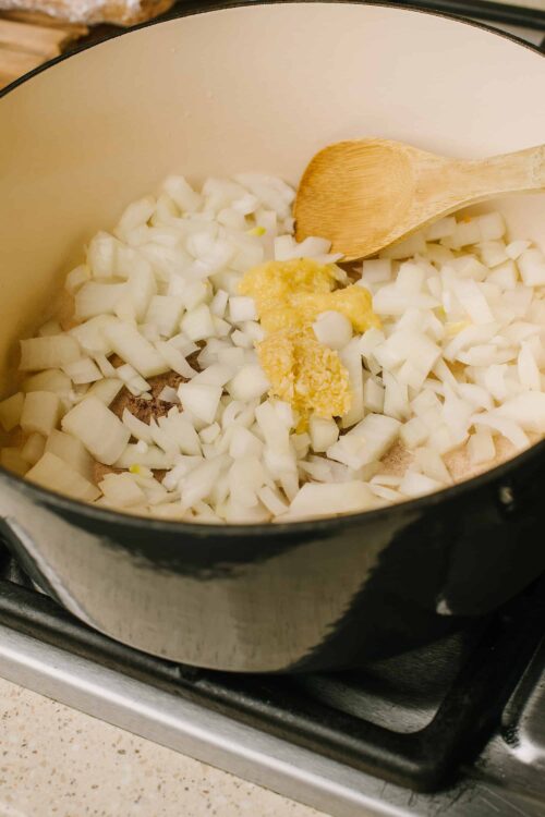 Diced onions and garlic cooking in a saucepan for homemade baking recipes.