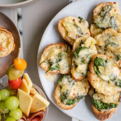 Golden spinach and cheese bruschetta on a white plate, perfect for appetizers or entertaining.