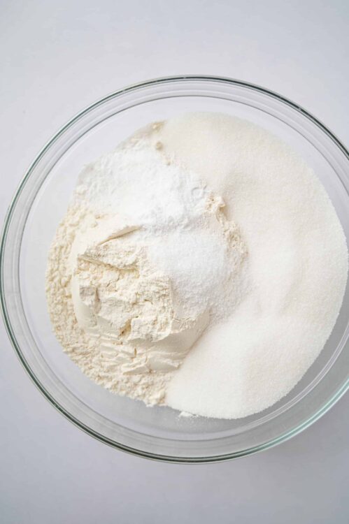 Flour, sugar, and baking ingredients in a glass bowl for baking.