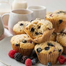 Fresh blueberry muffins with mixed berries on a white plate.