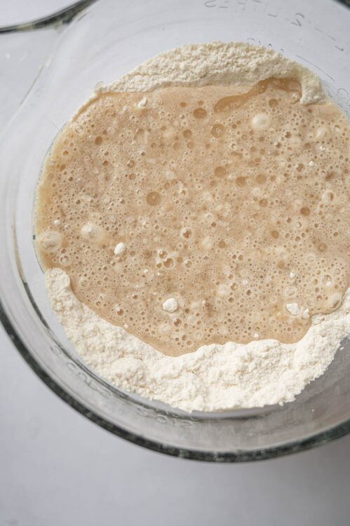 Flour and yeast mixture for bread dough preparation in a glass bowl.