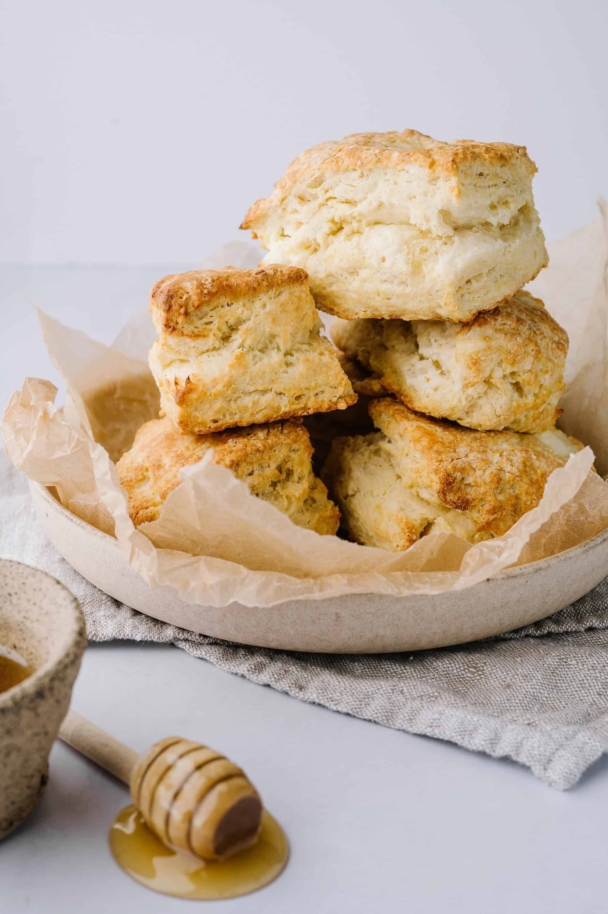 Buttermilk biscuits on parchment paper in a light-colored bowl, perfect for breakfast or brunch.