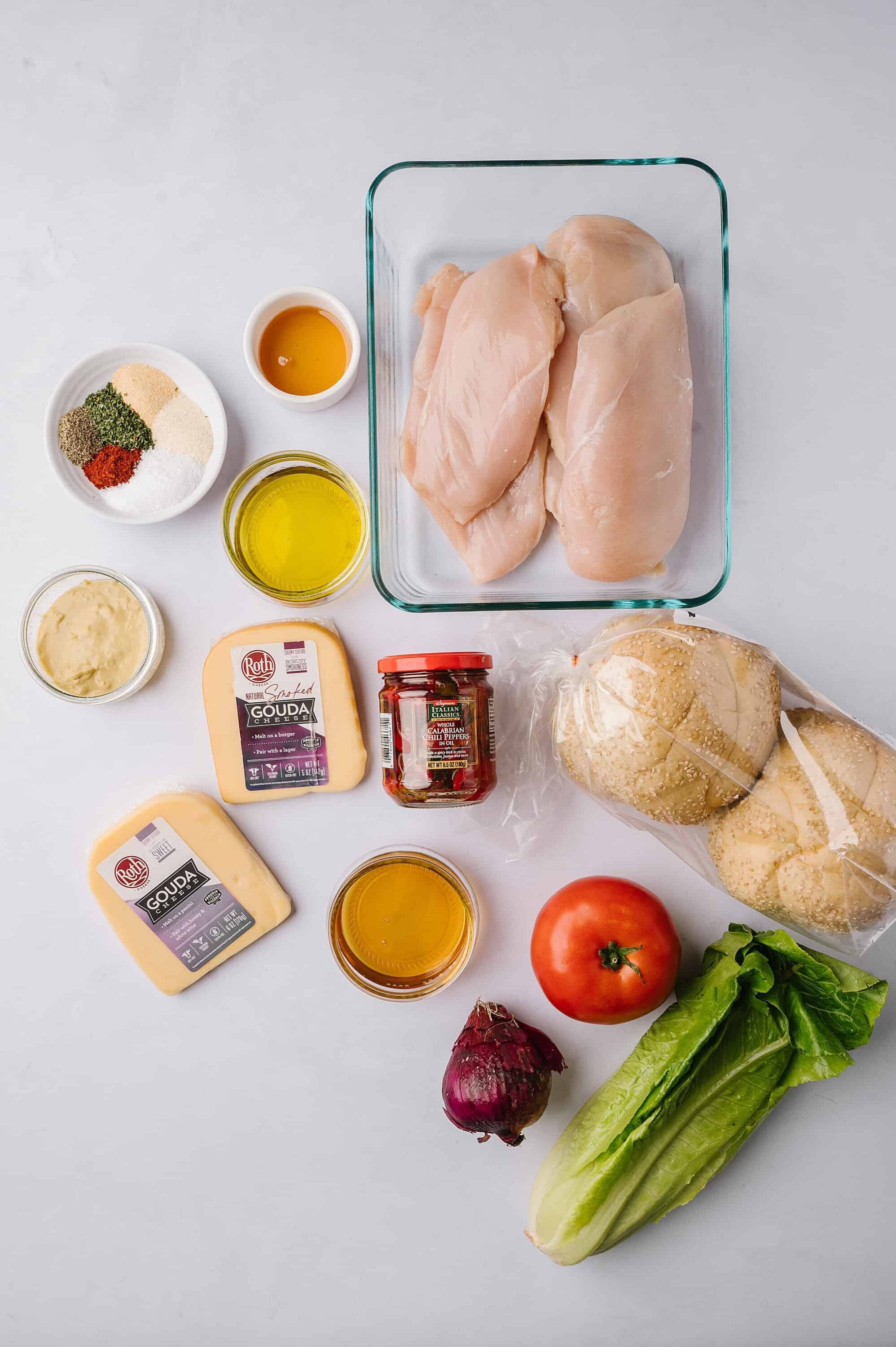 Raw chicken breasts with vegetables and cheese ingredients for homemade chicken sandwich or casserole dish.