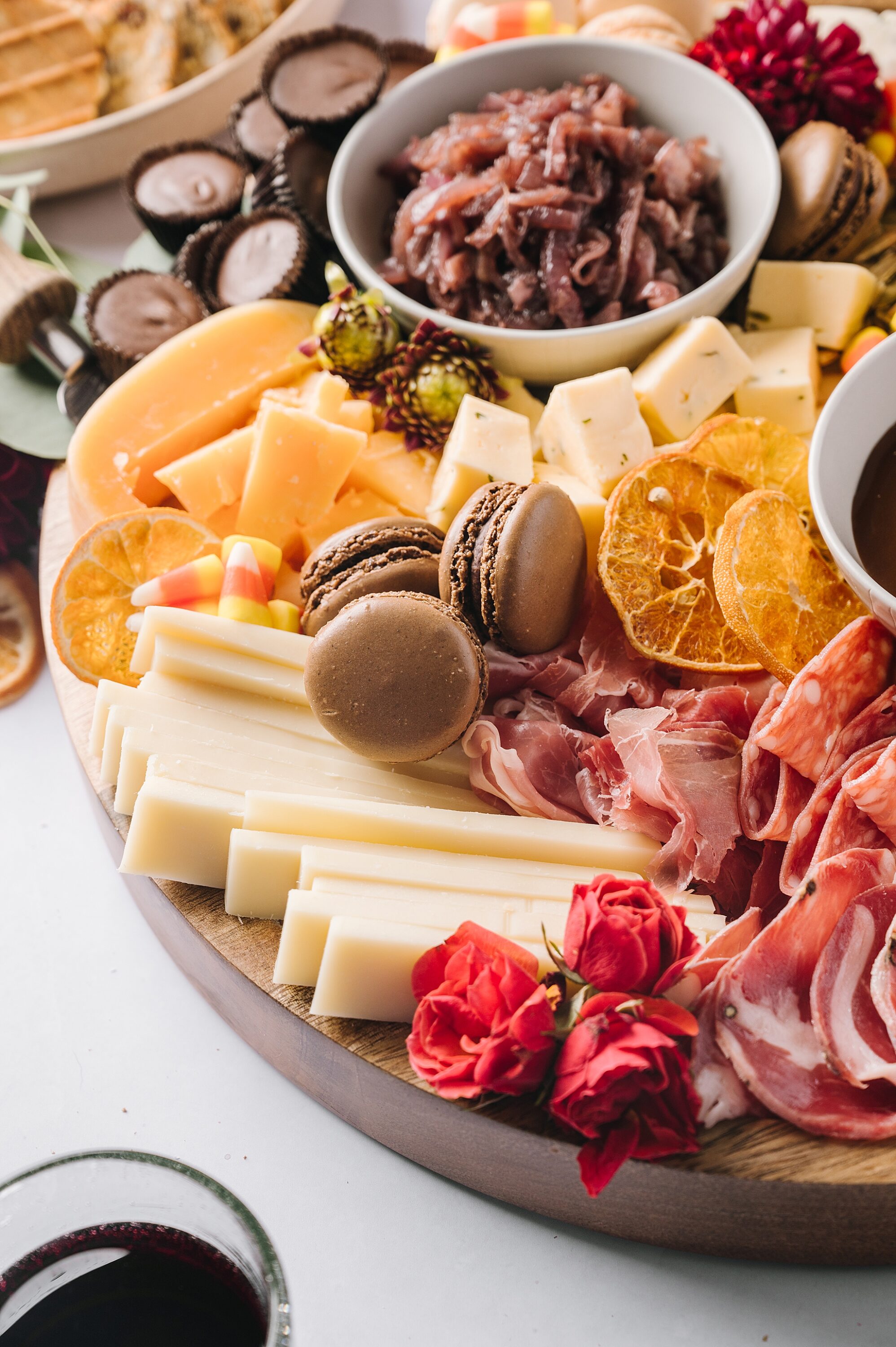 Cheese and charcuterie platter with cured meats, cheeses, crackers, dried orange slices, and chocolates for entertaining.