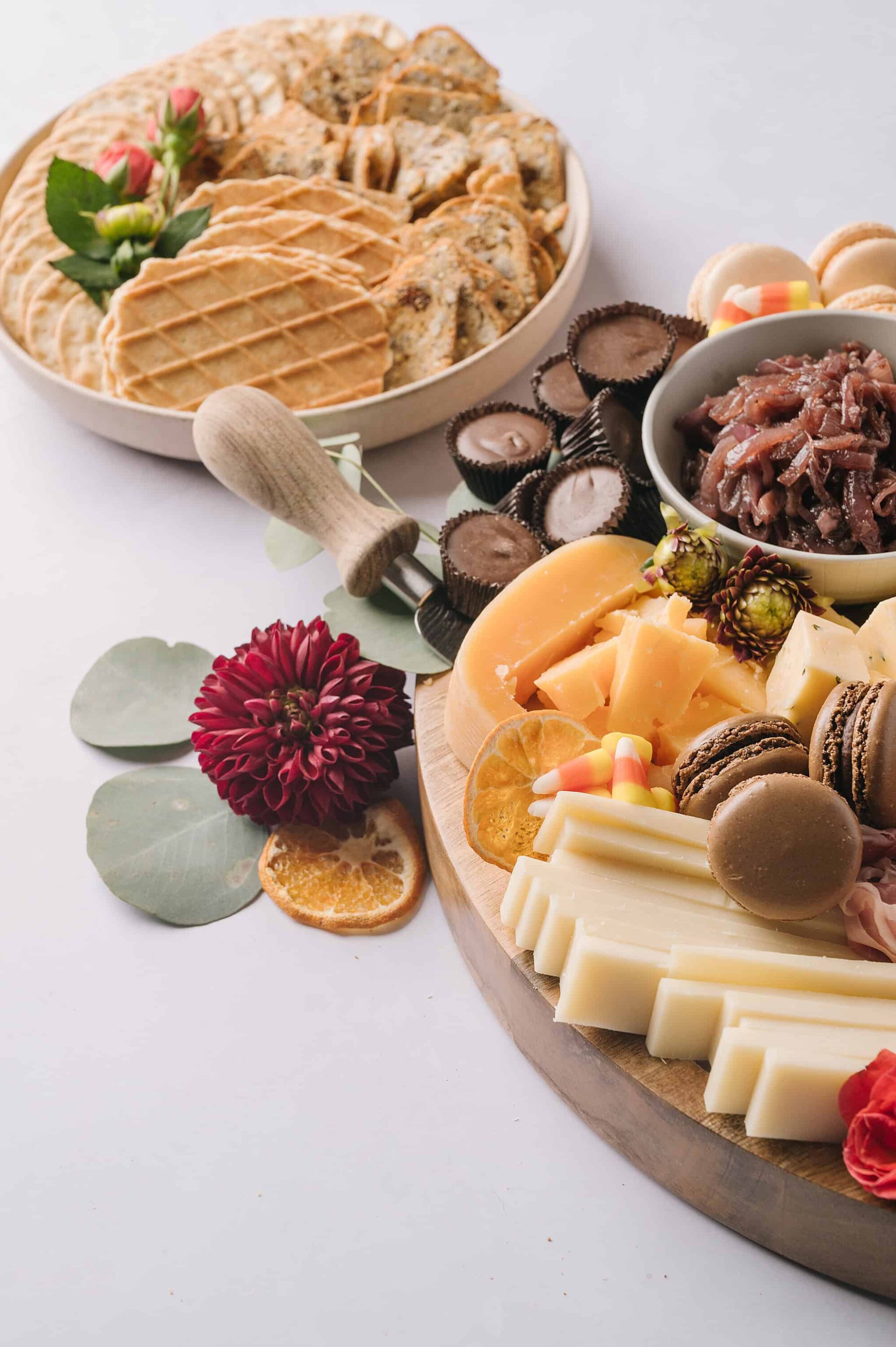 Buttery cheese and charcuterie platter with macarons, dried fruit, and sweets for entertaining.