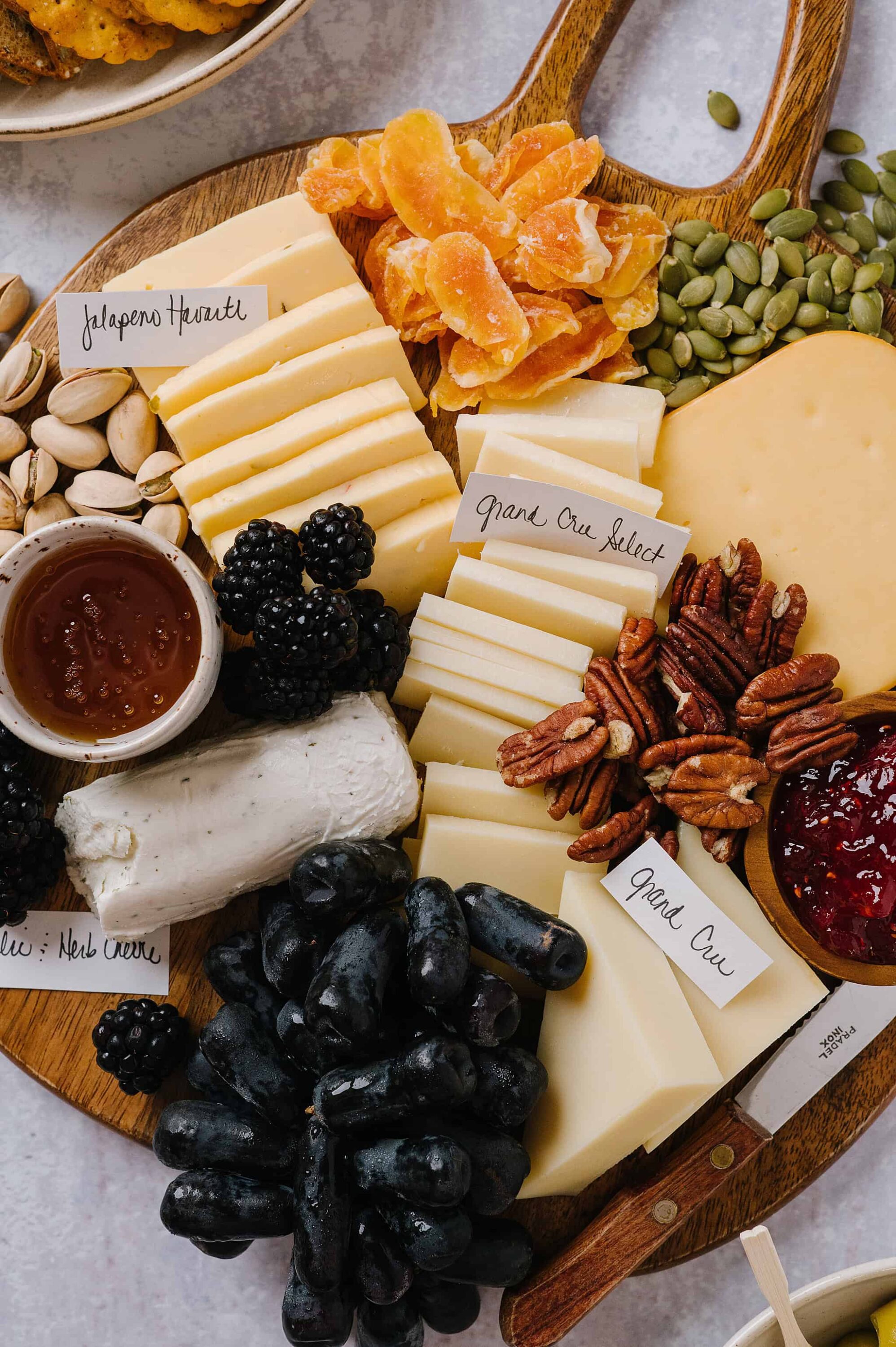 Cheese and fruit charcuterie board with nuts, blackberries, grapes, and jams for entertaining.