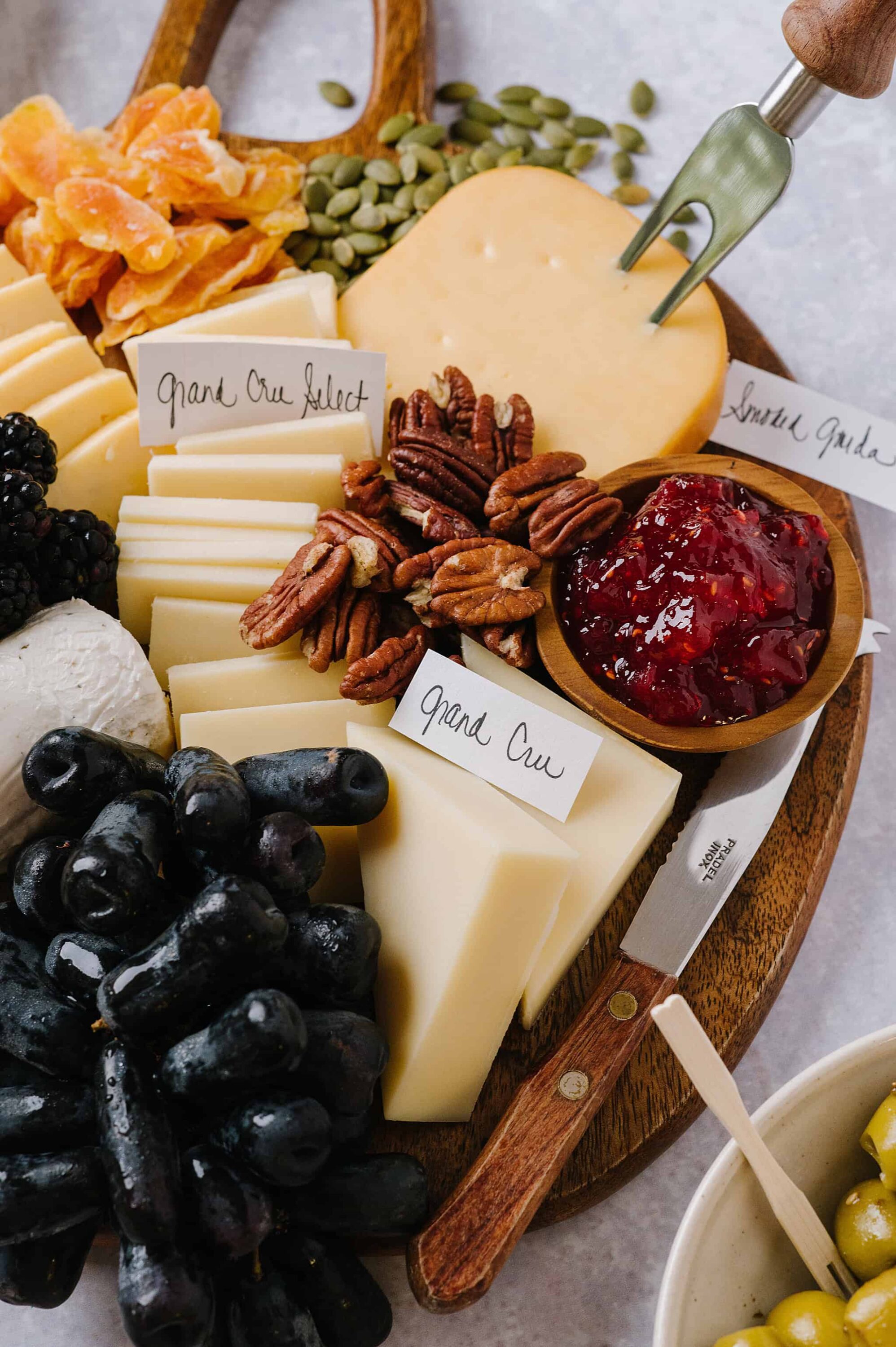 Cheese and charcuterie board with Gouda, Pecorino, nuts, berries, and jam, styled for food photography.
