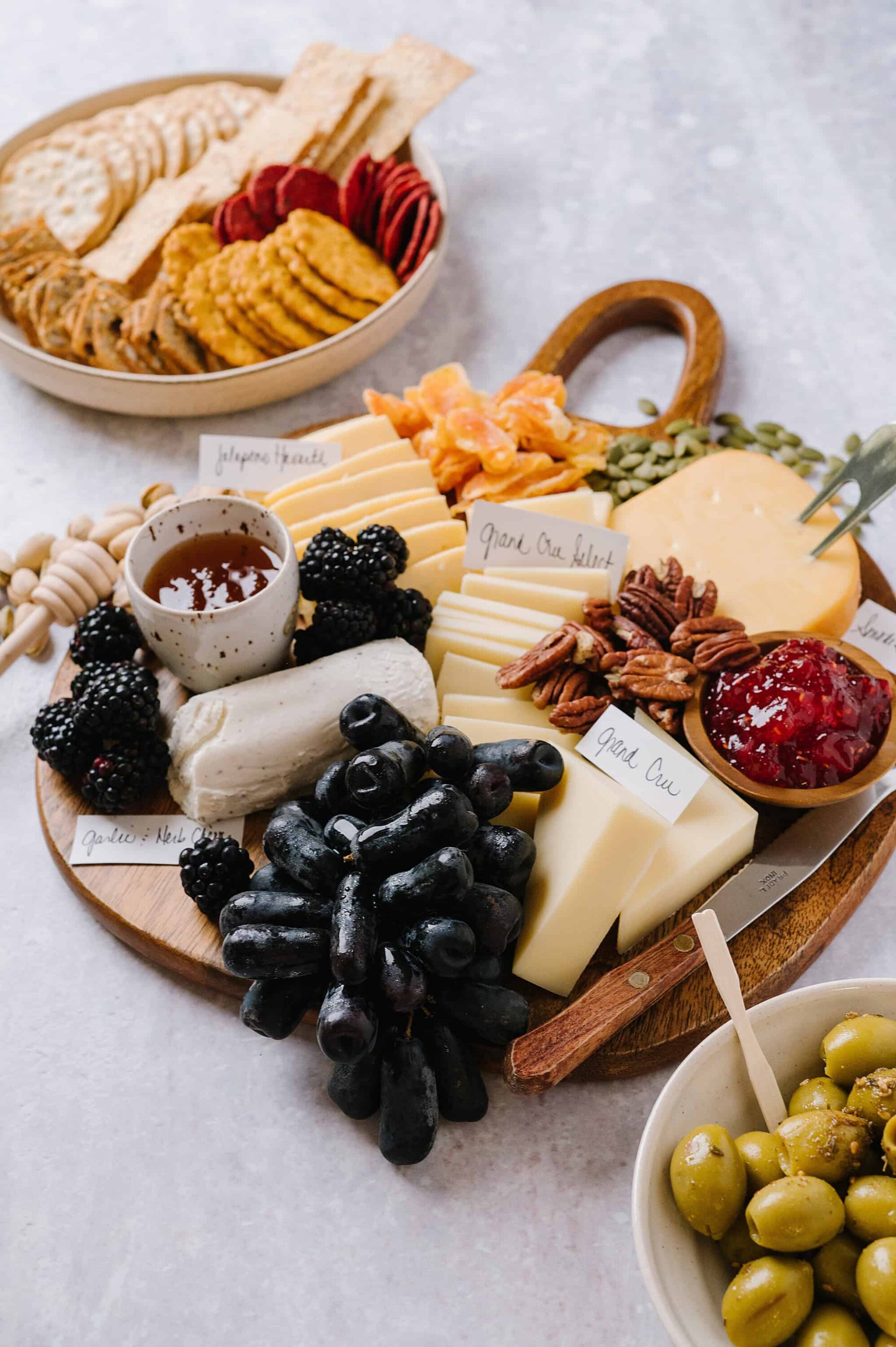 Assorted cheese and fruit platter with crackers and jams, perfect for entertaining or appetizer tables.