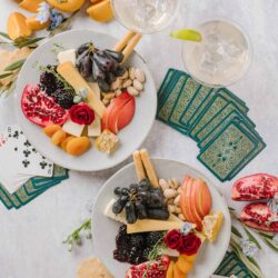 Fresh cheese and fruit platter with grapes, pomegranate, apple slices, dried apricots, and cheeses, perfect for entertaining.