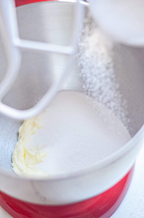 Flour being sifted into a mixing bowl with butter on a stand mixer.