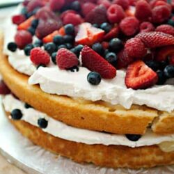 Fresh berry layer cake with whipped cream and mixed berries, perfect for summer desserts.