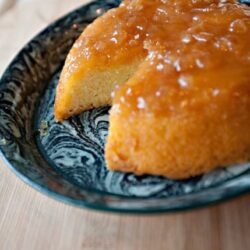 Golden caramel-glazed cake on decorative blue plate, fresh from the oven.
