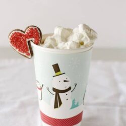 Fluffy whipped cream topped with a festive gingerbread cookie on a snowman-themed holiday mug.