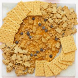 Crispy graham cracker crust with caramel and chocolate chips on baking sheet.