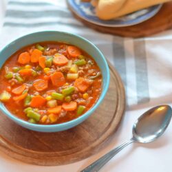 Comforting homemade vegetable beef stew in a blue bowl on a wooden board.
