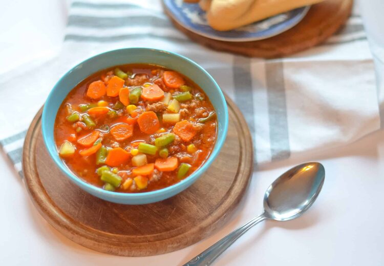Comforting homemade vegetable beef stew in a blue bowl on a wooden board.