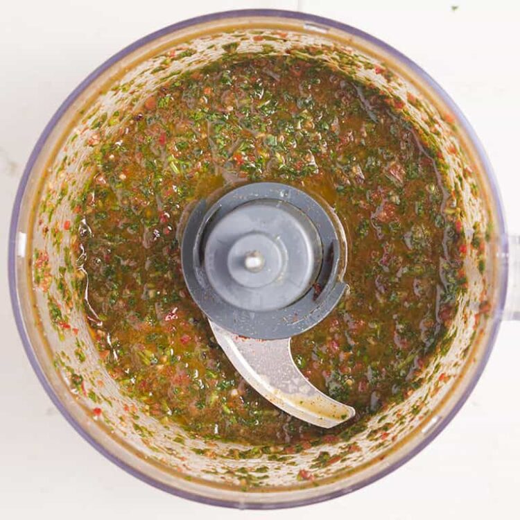 Brightly colored homemade salsa in a food processor.