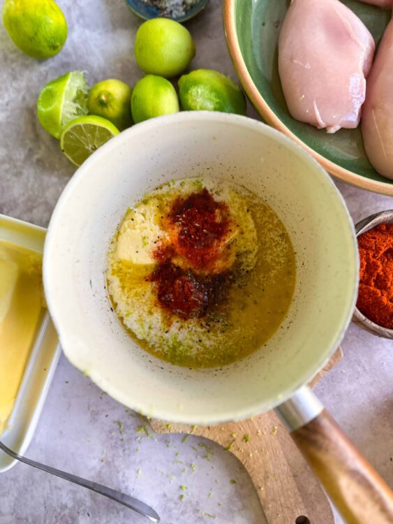 Lime juice, spices, and butter in a saucepan for cooking or seasoning.