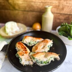 Fresh spinach and cheese stuffed chicken breasts cooked to golden perfection on a black skillet. Perfect for healthy dinnertime recipes.