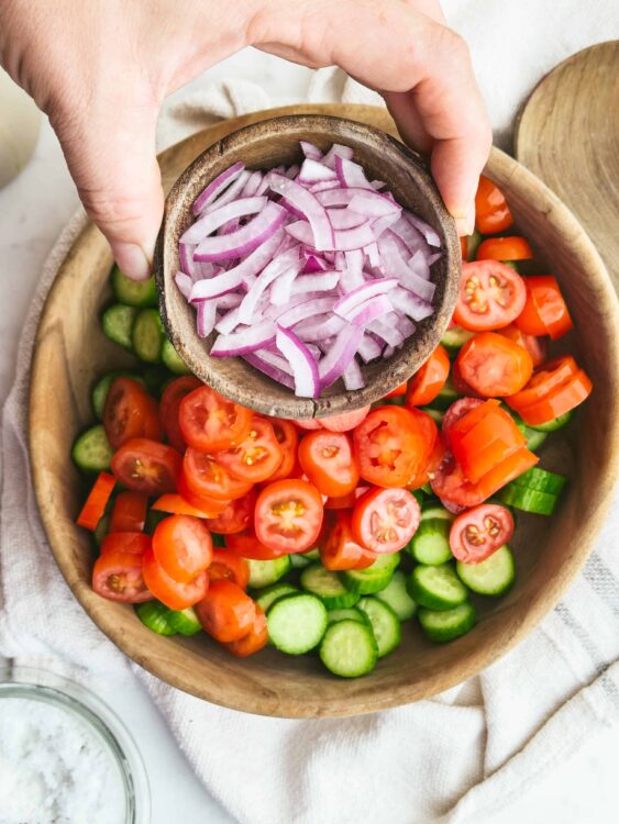 Freshly sliced red onions, tomatoes, and cucumbers for a healthy homemade salad. Perfect for summer meals and nutritious eating.