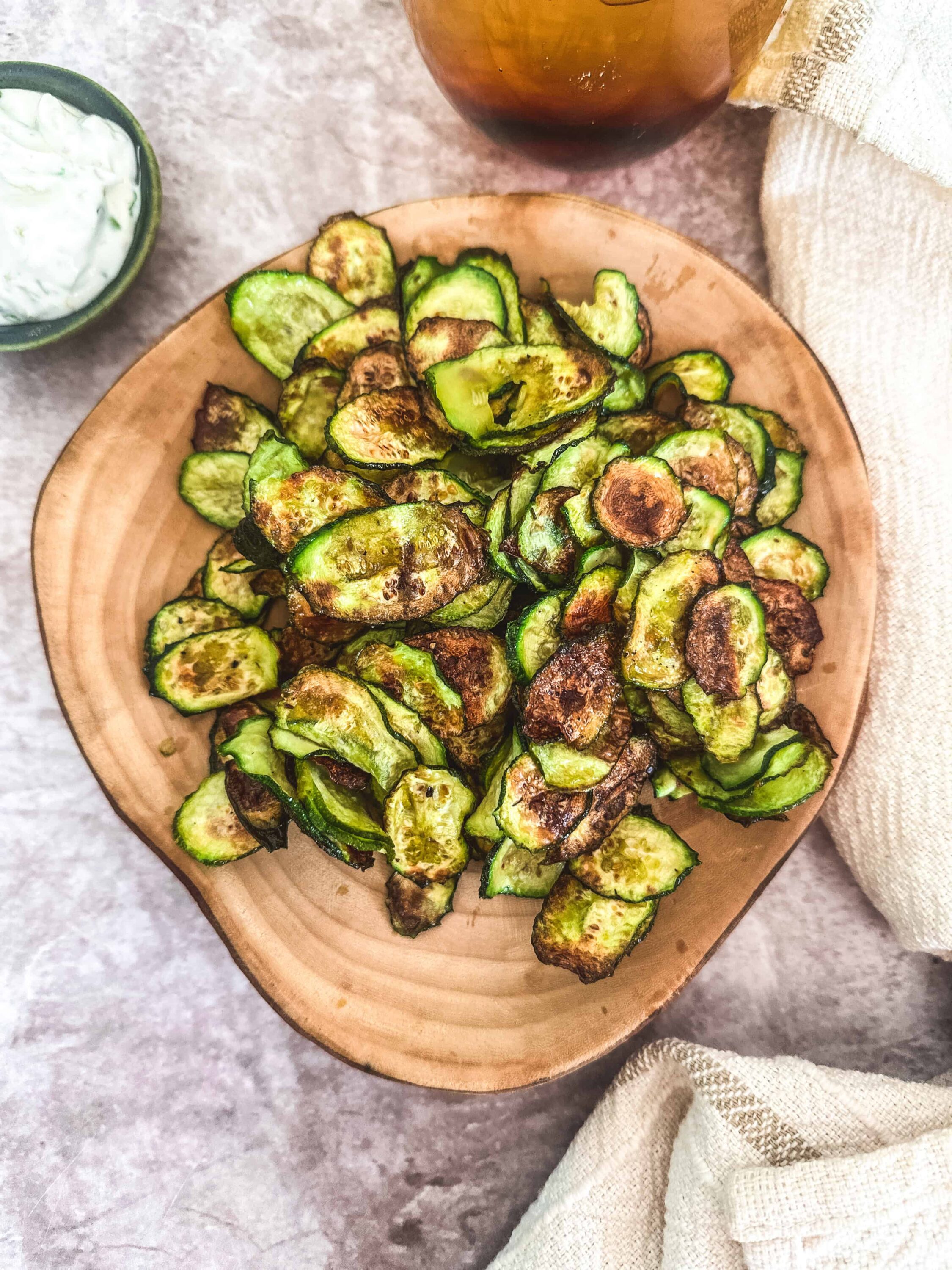 Crunchy roasted zucchini chips on a wooden plate, perfect healthy snack or appetizer.
