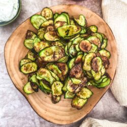 Crunchy roasted zucchini chips on a wooden plate, perfect healthy snack or appetizer.