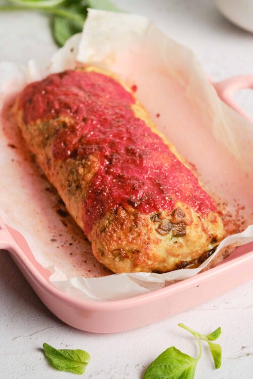 Baked meatloaf with tomato glaze in a pink baking dish.