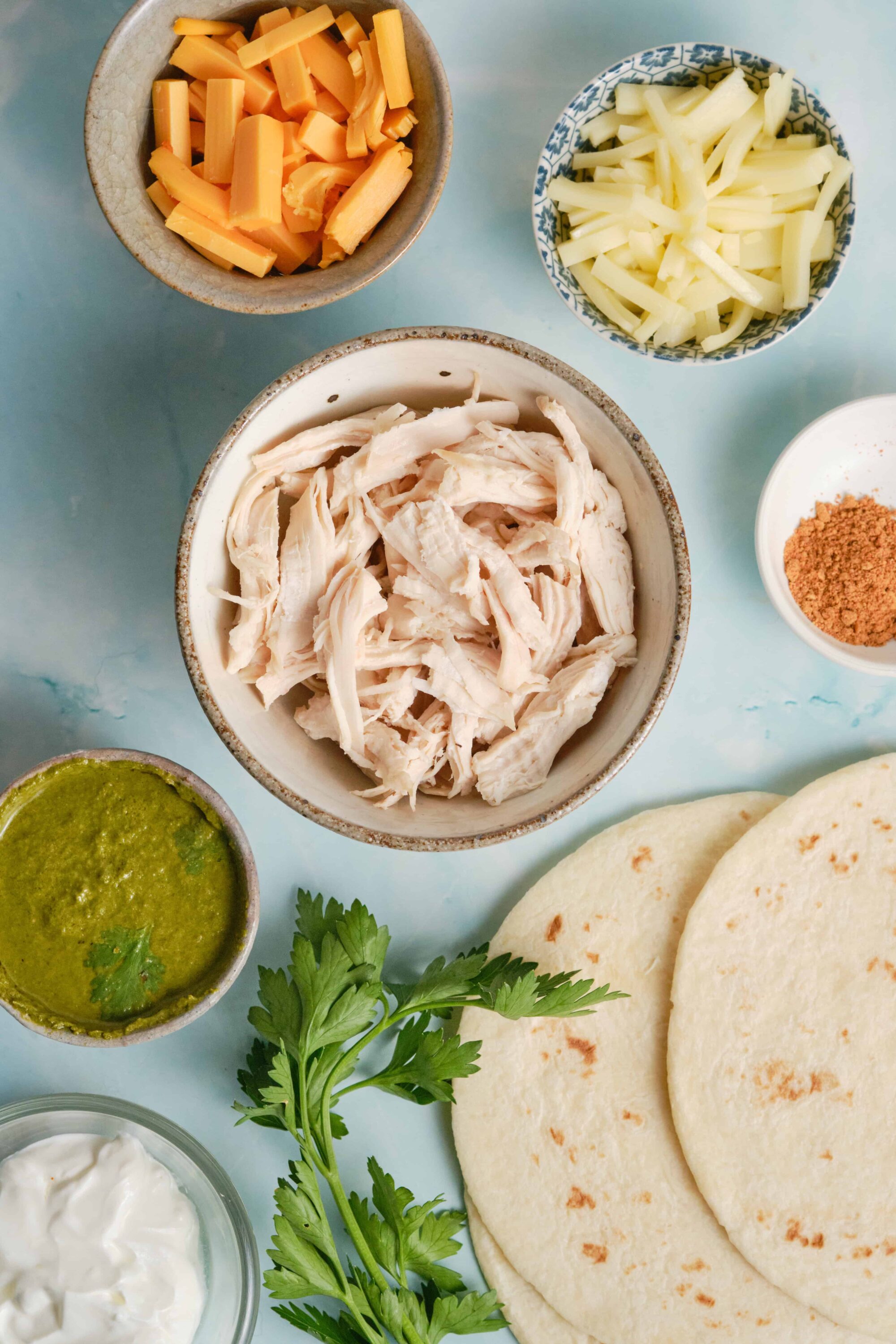 Shredded chicken, cheese, and taco ingredients for homemade tacos.