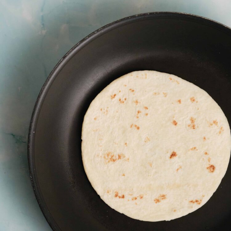 Soft flour tortilla cooking in a non-stick skillet.