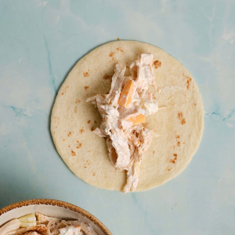 Creamy chicken salad on tortilla wrap ready to roll, perfect for sandwiches or snacks, easy to make delicious meals.