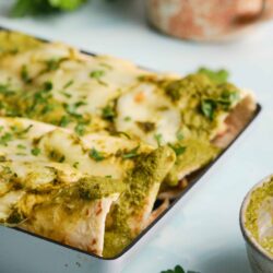 Baked chicken enchiladas with green sauce and melted cheese.