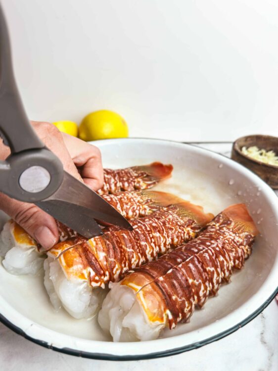 Freshly prepared seafood casserole with lobster tails topped with a drizzle of sauce and garnished with chopped garlic.