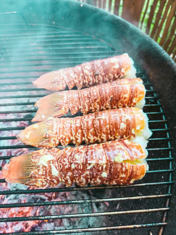 Fresh lobster tails grilling on barbecue for seafood dinner.