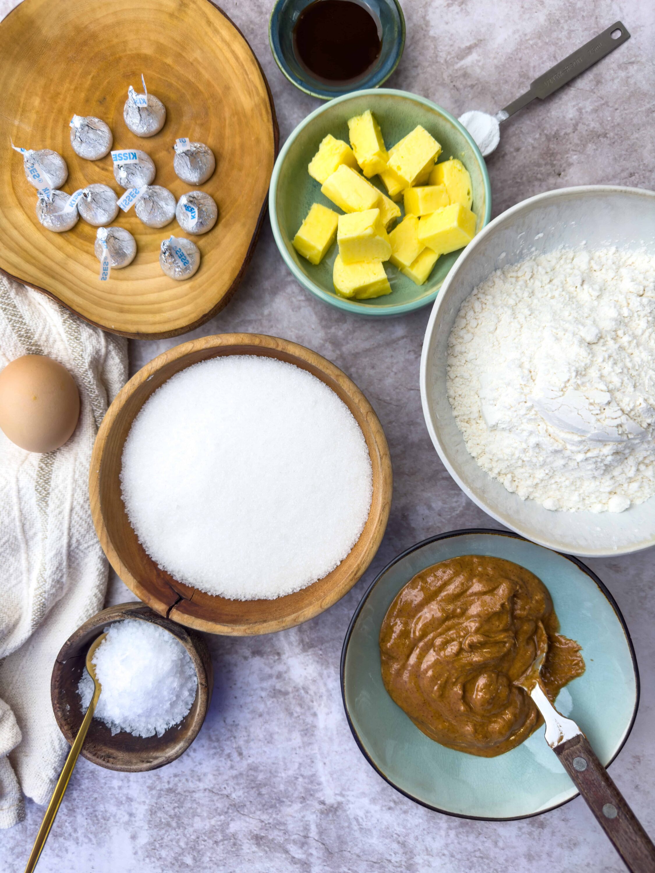 Butterscotch chips, butter, flour, sugar, egg, vanilla extract, and salt on a kitchen table for baking cookies.
