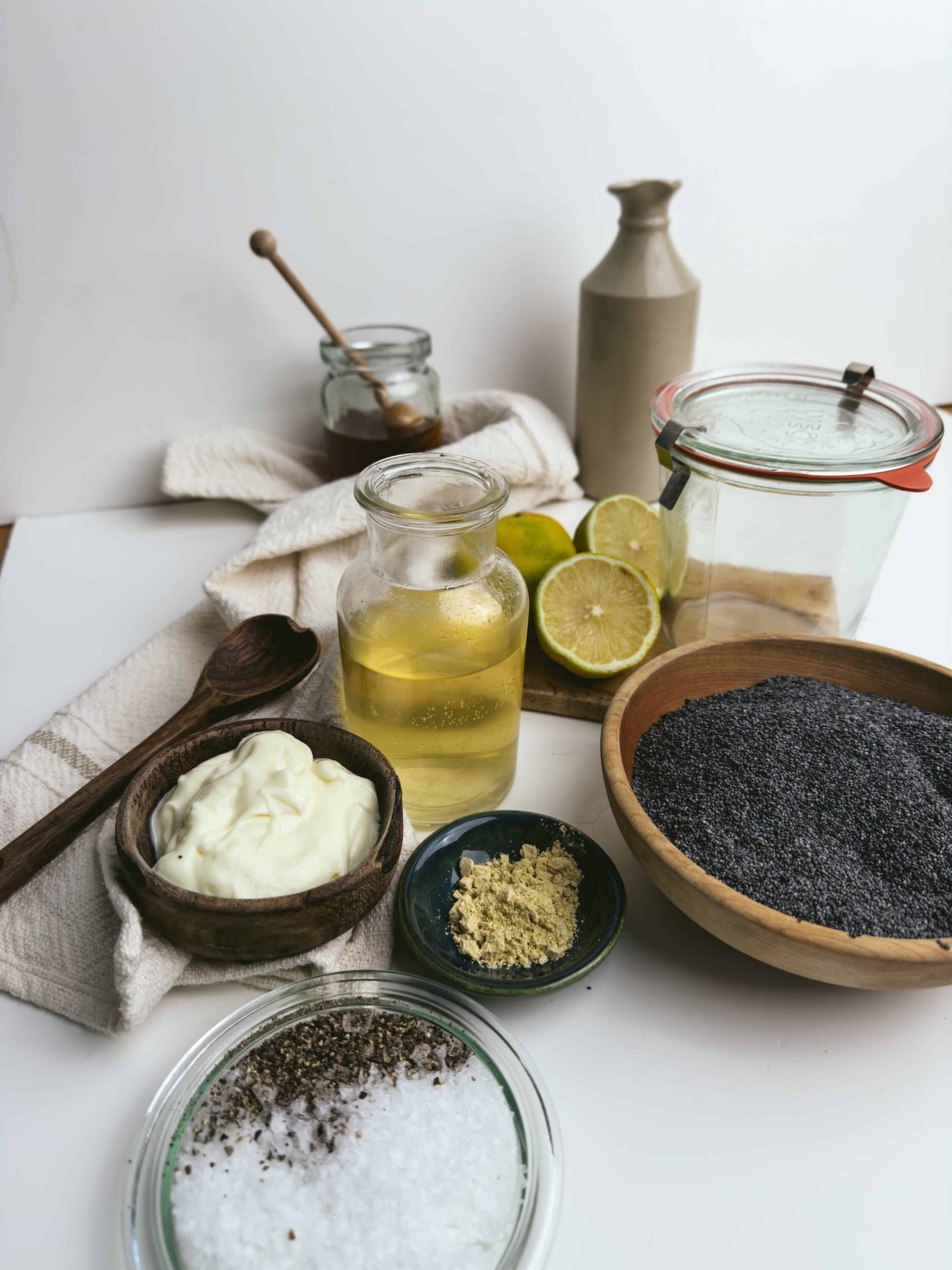 Fresh ingredients for baking including lemon, black sesame seeds, matcha powder, yogurt, honey, and salt.