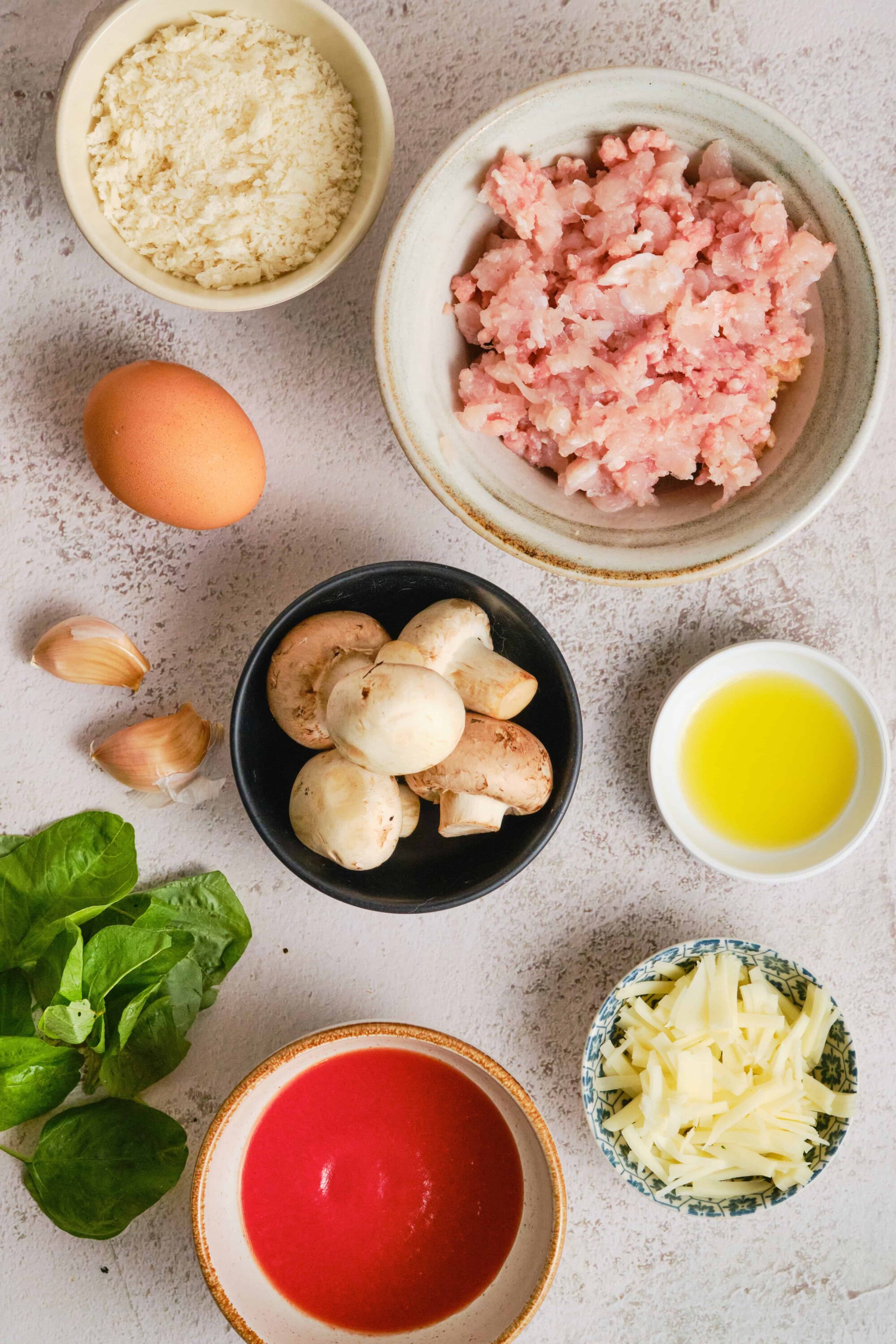 Minced chicken, mushrooms, cheese, tomato sauce, and fresh herbs ready for cooking.