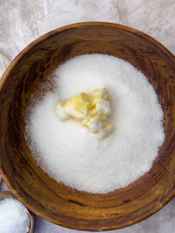 Granulated sugar and butter in a wooden bowl for baking.