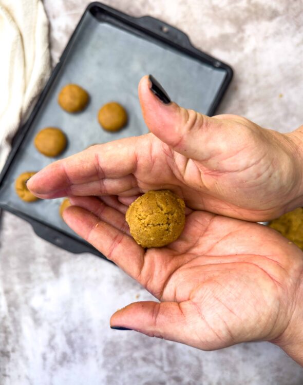 Soft baked cookie dough ball in hand, ready for baking.