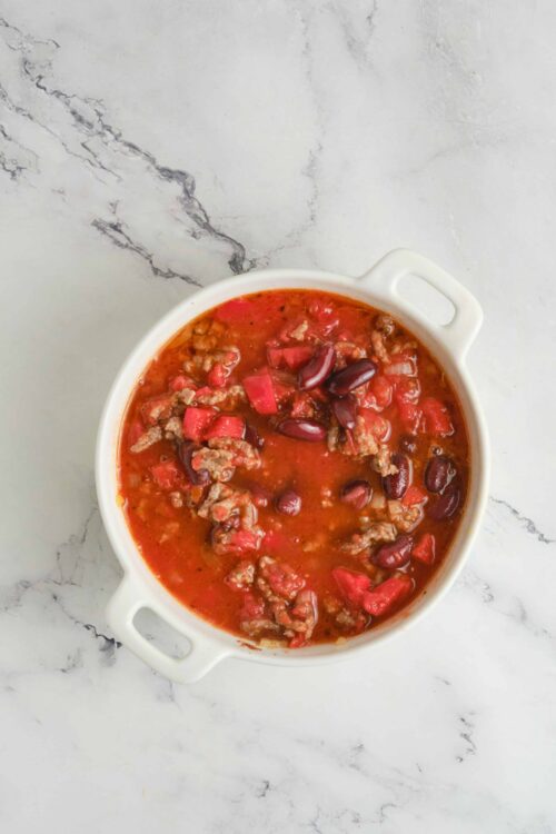 Hearty homemade chili with beans, ground beef, and tomatoes in a white serving bowl.