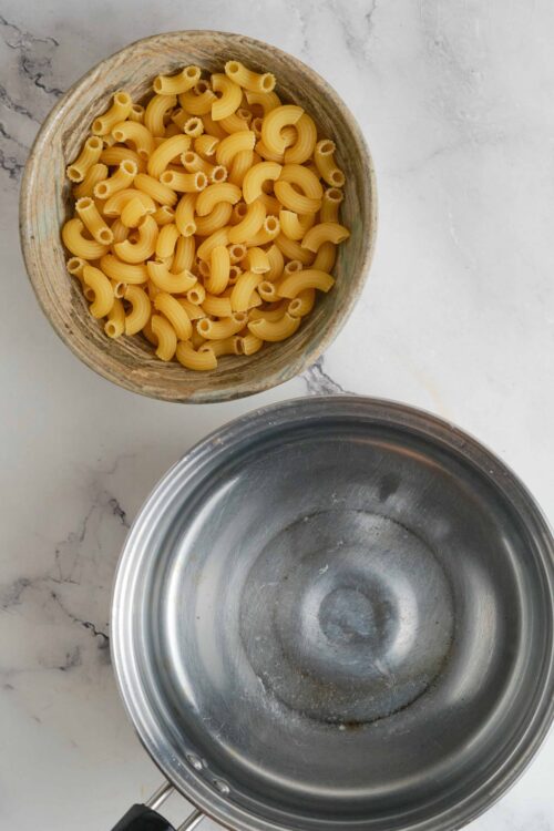 Cooked pasta in a rustic bowl, with an empty pot beside it, ready for cooking or baking. Perfect for homemade pasta recipes on Baked Bree.