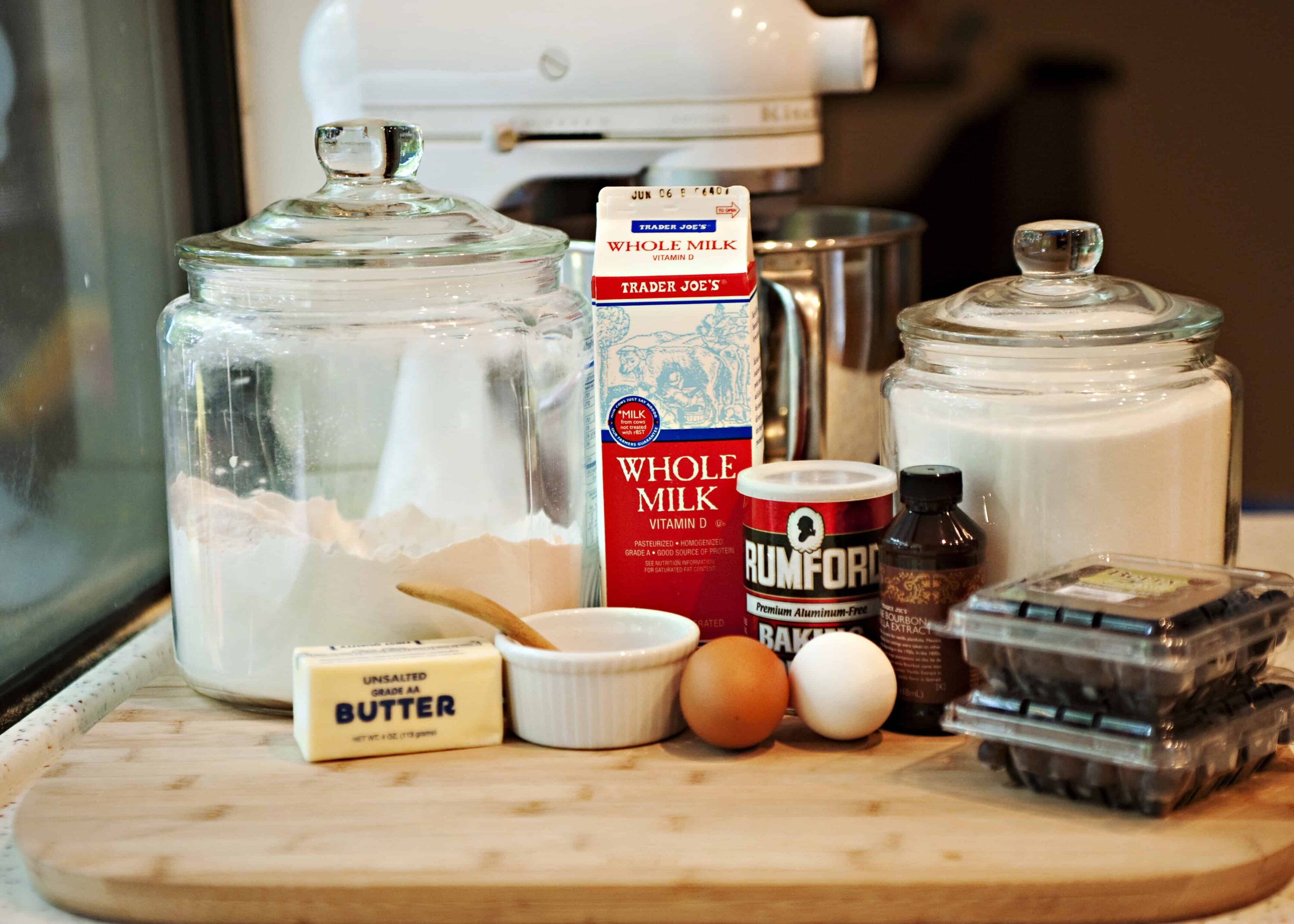 Flour, milk, eggs, butter, baking ingredients on kitchen countertop for baking.