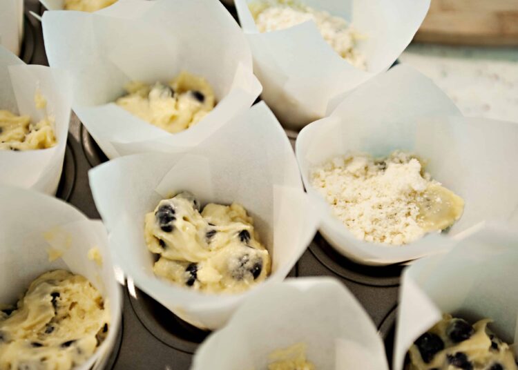 Fresh blueberry muffin batter in paper cups ready for baking at Baked Bree.