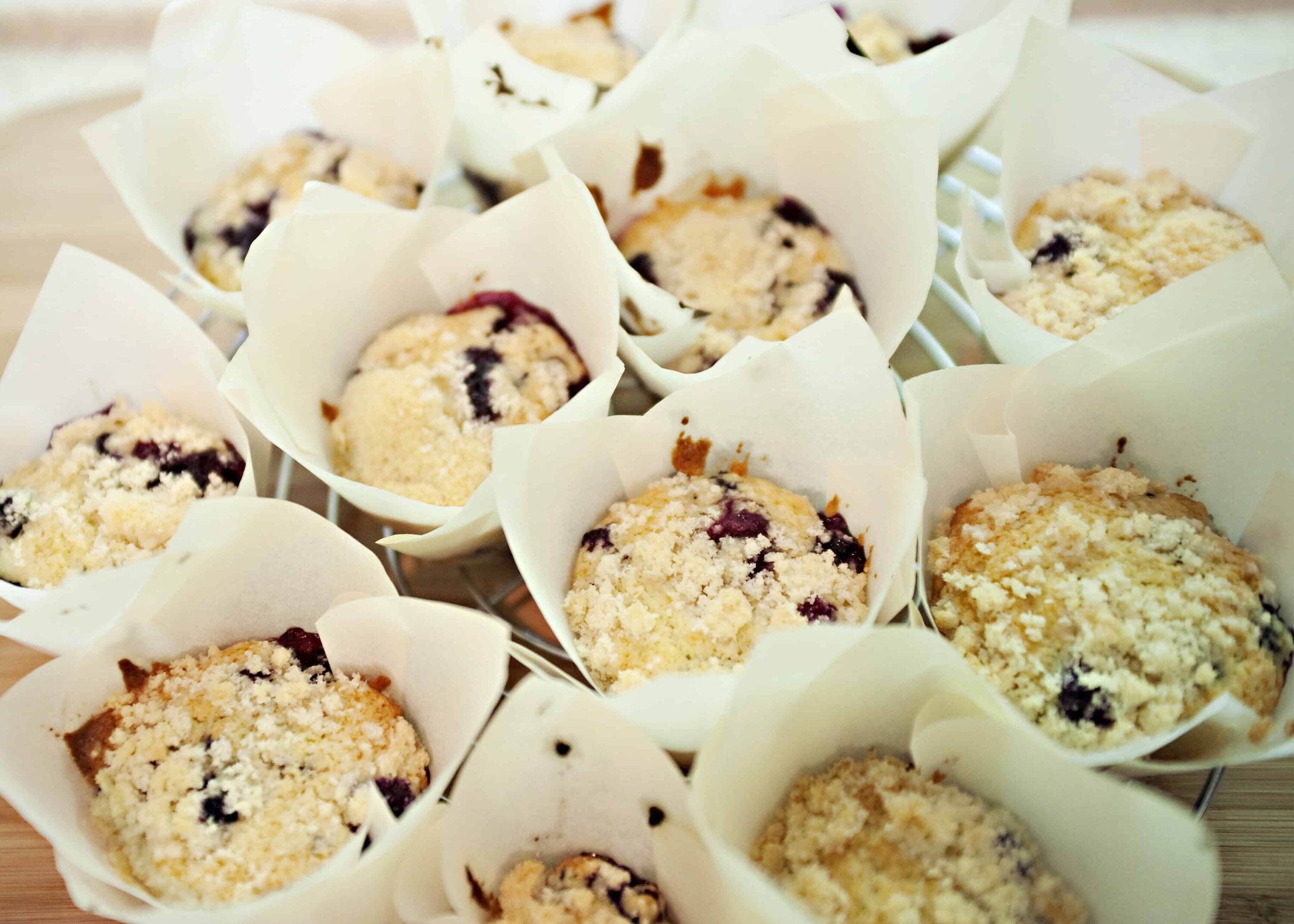 Delicious mixed berry crumb muffins in white paper cupcake liners.