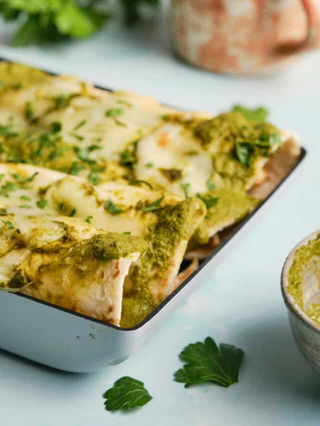 Cheesy chicken enchiladas with green sauce on a baking dish.